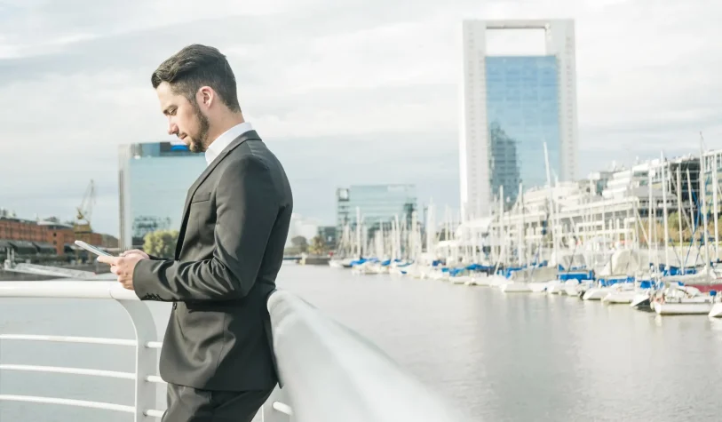 young-businessman-standing-near-railing-using-mobile-phone